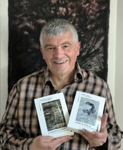 Christophe Havot avec les deux derniers livres édités, devant une œuvre de Laurent Maginelle